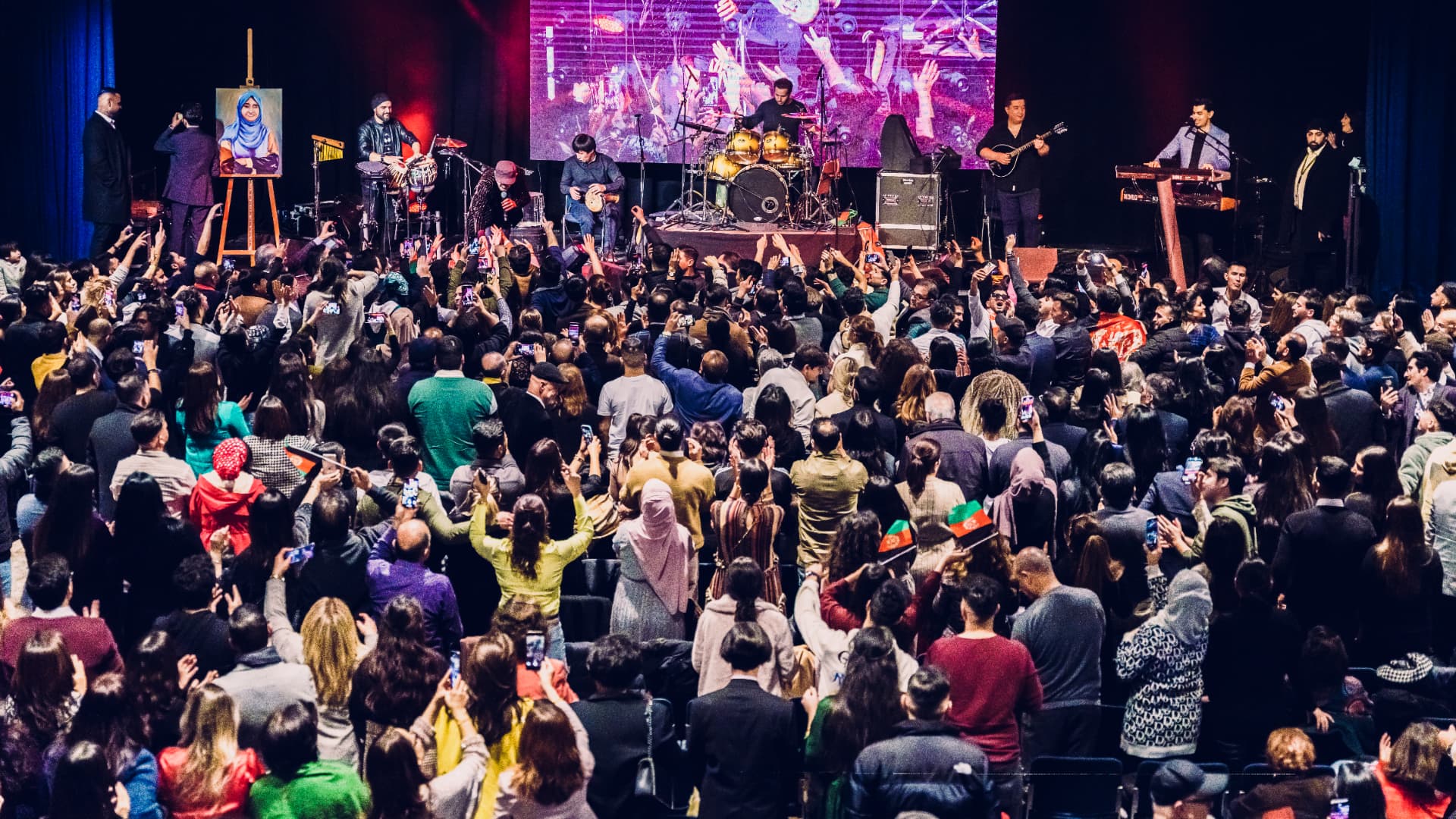 Audience waving Afghan flags at a stagEvent concert